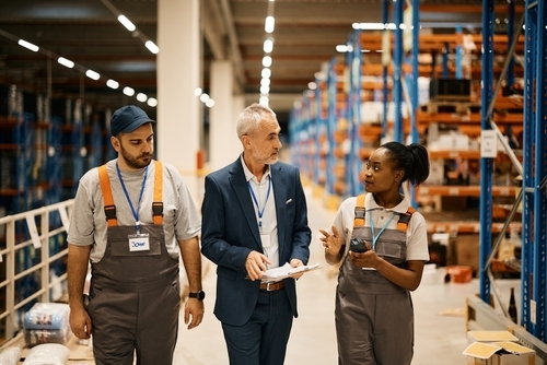 owner walking through a warehouse with employees