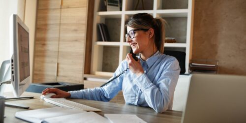 Businesswoman in her office.She sitting at the desk and talking on the phone.