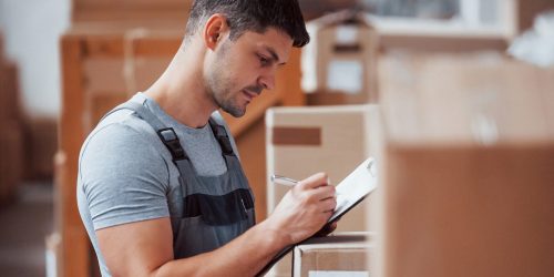 Storage worker in uniform and notepad in hands checks production Storage worker in uniform and notepad in hands checks production